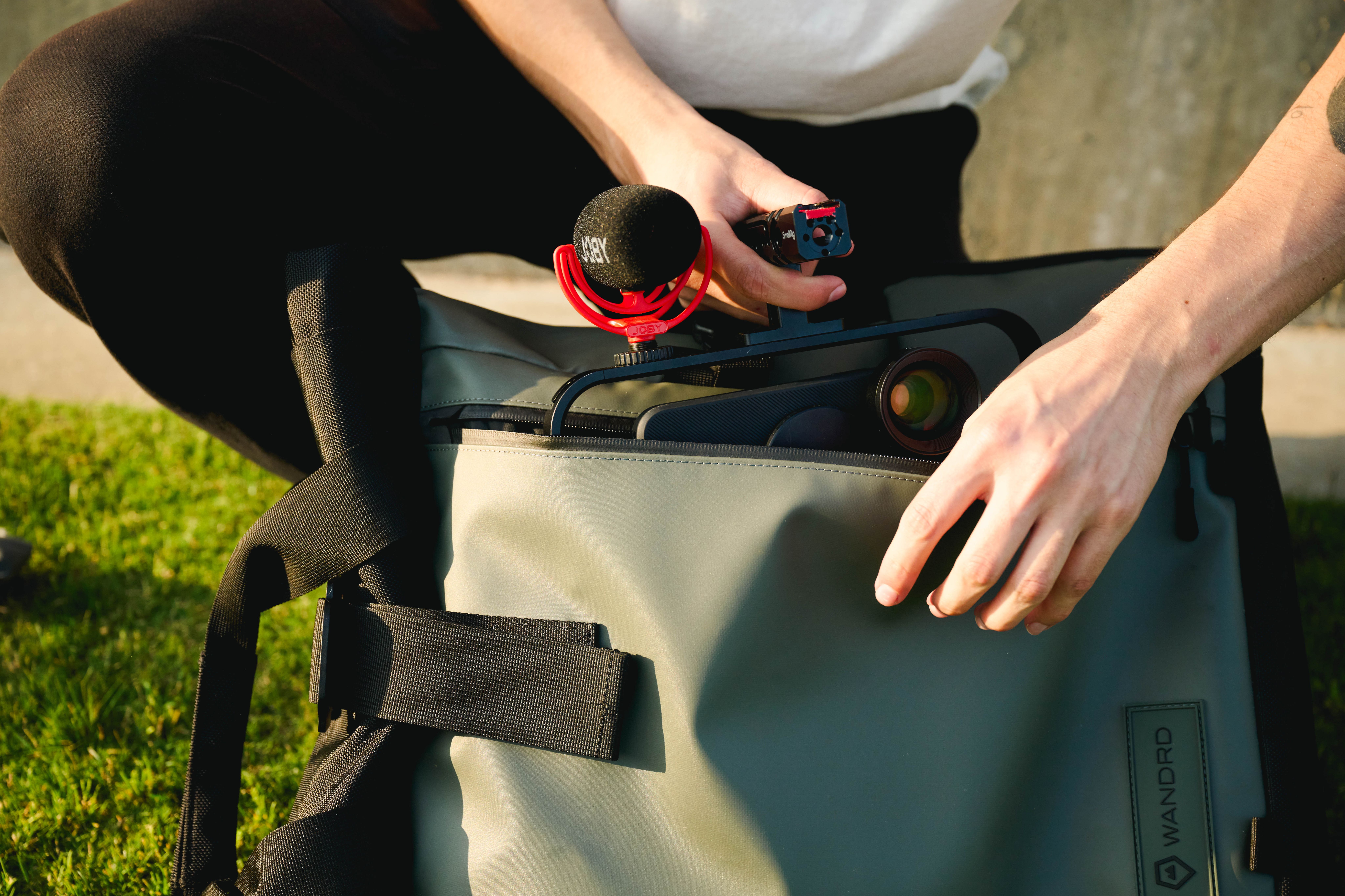 Placing iPhone into WANDRD backpack with a JOBY mic.